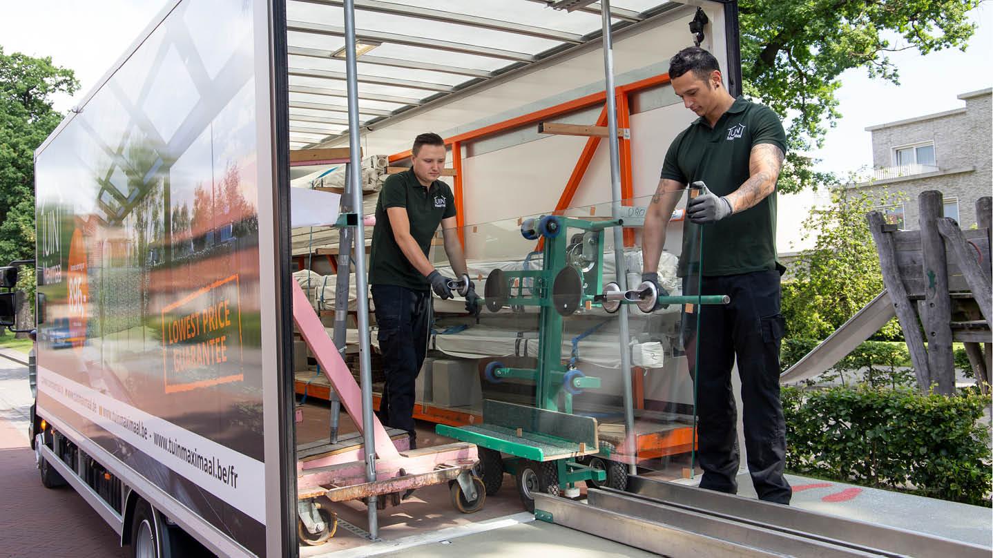 Déchargement d'une paroi coulissante en verre Des collaborateurs de Tuinmaximaal déchargent une paroi coulissante en verre d'un camion de livraison