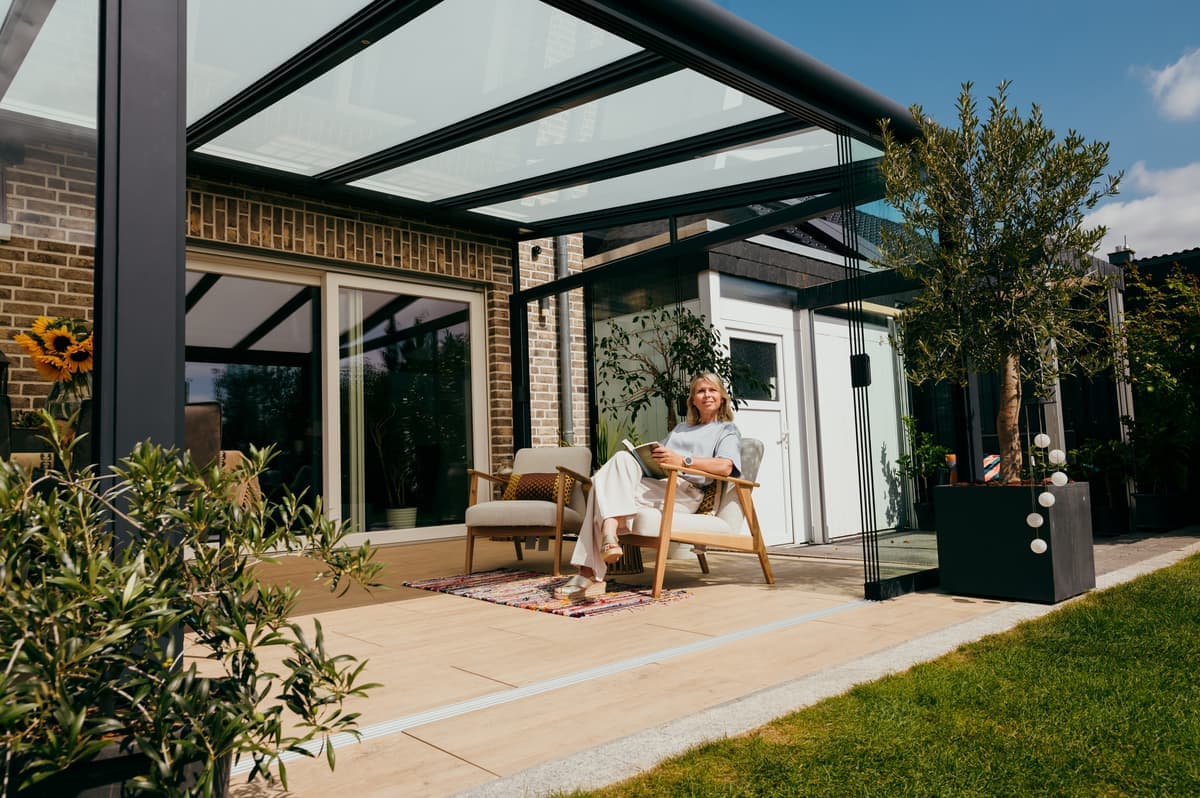 Premium look met een glazen dak Een moderne veranda met glazen dak creëert een lichte en ontspannen sfeer in de tuin.