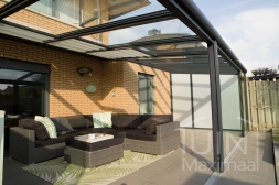 Véranda en anthracite mat avec panneaux de toit en verre, protection solaire et spots LED