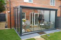 Antraciete terrasoverkapping met glazen schuifwanden en polycarbonaat zijwanden Antraciete terrasoverkapping met glazen schuifwanden en polycarbonaat zijwanden