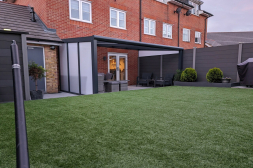 Antraciete terrasoverkapping met een polycarbonaat zijwand en een spie op schutting Antraciete terrasoverkapping met een polycarbonaat zijwand en een spie op schutting